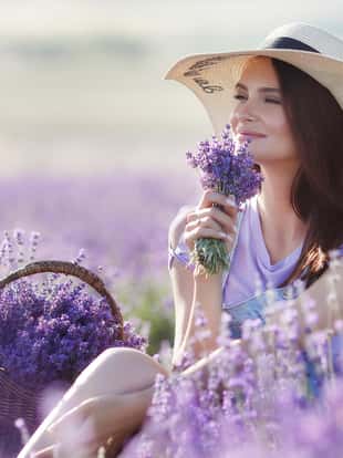 Cute smiling pregnant woman resting in a lavender field. Posing outdoors. Motherhood. Motherhood.Lavender field and a happy pregnant woman.Young beautiful pregnant woman in a hat from the sun on summer meadow in grass on bright Sunny day.