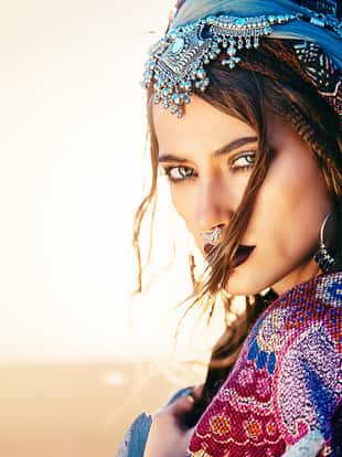 Beautiful fashion model posing in boho style clothes in the rays of the sunset. Outdoor fashion.