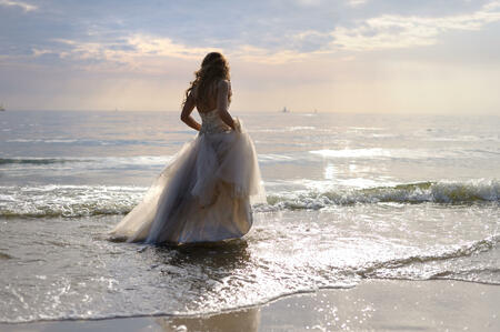 Bride walking along sea coast in the wedding dress