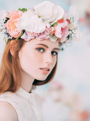 A portrait of a lovely beautiful girl with a wreath of flowers on the head on a floral background. Beauty, cosmetics.