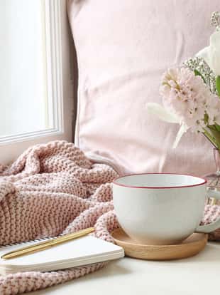 Cozy Easter, spring still life scene. Cup of coffee, notebook, golden pen, pink knitted plaid near window. Vintage feminine styled photo, floral composition with tulips, hyacinth and Gypsophila flowers.