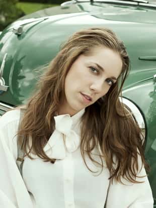 Woman at a vintage car. 1950-1960 style. Desatured and toned image.