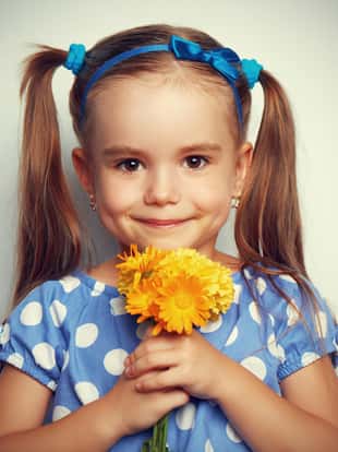Beauty child girl in a blue dress with a bouquet of yellow flowers