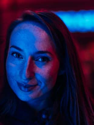 Portrait of a young woman illuminated by neon city lights
