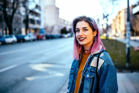 Girl with colorful hair at city street.