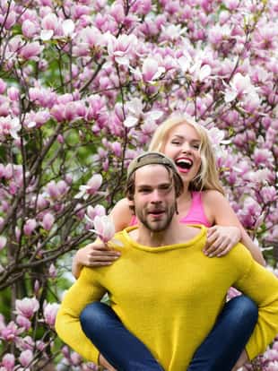 romantic couple in love in spring garden at beautiful blooming magnolia tree