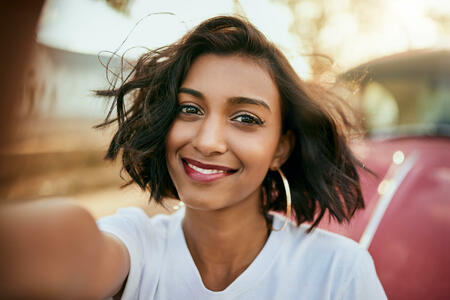 Cropped portrait of an attractive young woman standing against her car and taking a selfie alone during a day out