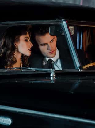 selective focus of man touching steering wheel and sitting near attractive woman in retro car
