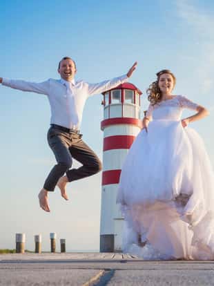 Beautiful young wedding couple on the pier in front of lighthouse
