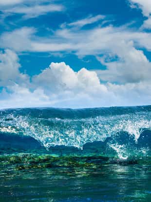 Tropical ocean with shorebreak. Surfing wave splashing on coral reef. Maldivian paradise with clouds on blue sky in daylight. View point from inside the wave