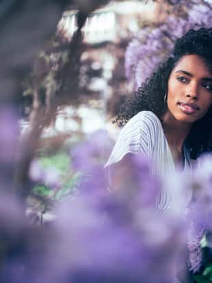 Young black woman sitting surrounded by flowers