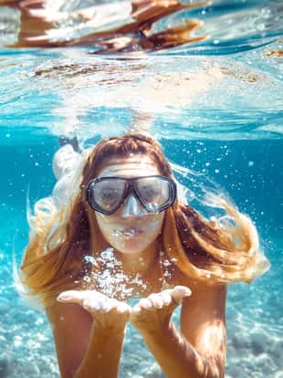 Snorkeling woman blowing a kiss underwater in the tropical sea