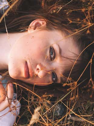 Portrait of Beauty Teenage Model Girl with Brown Hair on the Background of Nature on the Field in Sun Light. Face of Young Woman with Freckles. Autumn. Glow Sun, Sunshine. Warm Color Tones