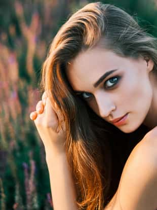 Portrait of beautiful young woman posing in sage field in summer sun. Outdoors, fashion, beauty concept