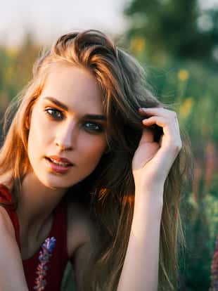 Portrait of beautiful young woman posing in sage field in summer sun. Outdoors, fashion, beauty concept