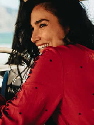 Rear view of young woman sitting on driver seat of a car and smiling. Female on a road trip traveling by car.