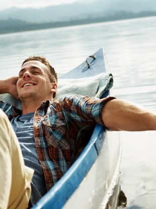 An attractive young man relaxing and daydreaming in a canoe