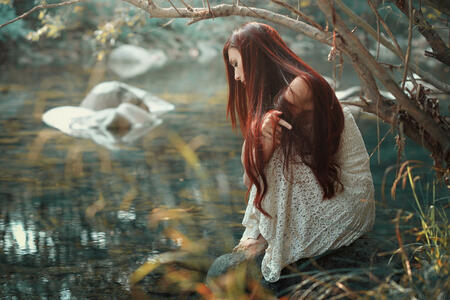 Thoughtful red hair woman looking at stream waters. Autumn colors