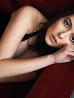 Young beautiful woman portrait posing on red sofa. Female beauty concept