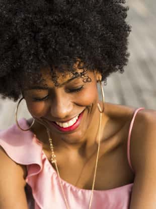 close up portrait of  a Happy young beautiful afro american woman sitting on wood floor and smiling. Spring or summer season. Casual clothing