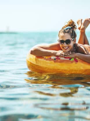 A beautiful young woman swims on inflatable ring donut at the sea water and enjoys on vacation.