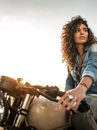 Beautiful female biker driving a cafe' racer motorbike - Pretty girl driving a motorbike and enjoying the roadtrip