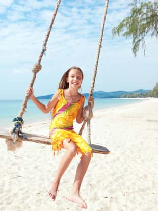 Girl sitting on the swing on the tropical beach, paradise island