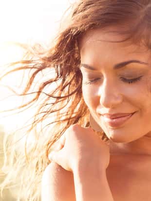 Closeup Of Smiling Young Woman With Eyes Closed At Sunset