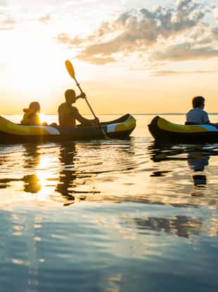 Family enjoy sea kayaking in the sunset.