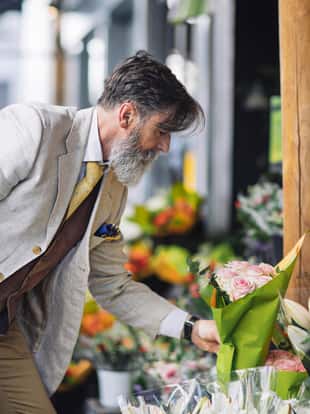 French mature man buying flowers in flower shop at Paris.