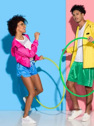 Sporty couple standing with hoops on pink and blue background