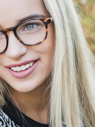 college student, a young woman, blonde, glasses, outdoors in the park