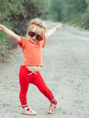 little girl dancing in glasses outdoors
