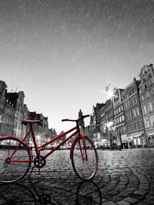 Vintage red bike on cobblestone historic old town in rain. Color in black and white. The market square at night. Wroclaw, Poland.